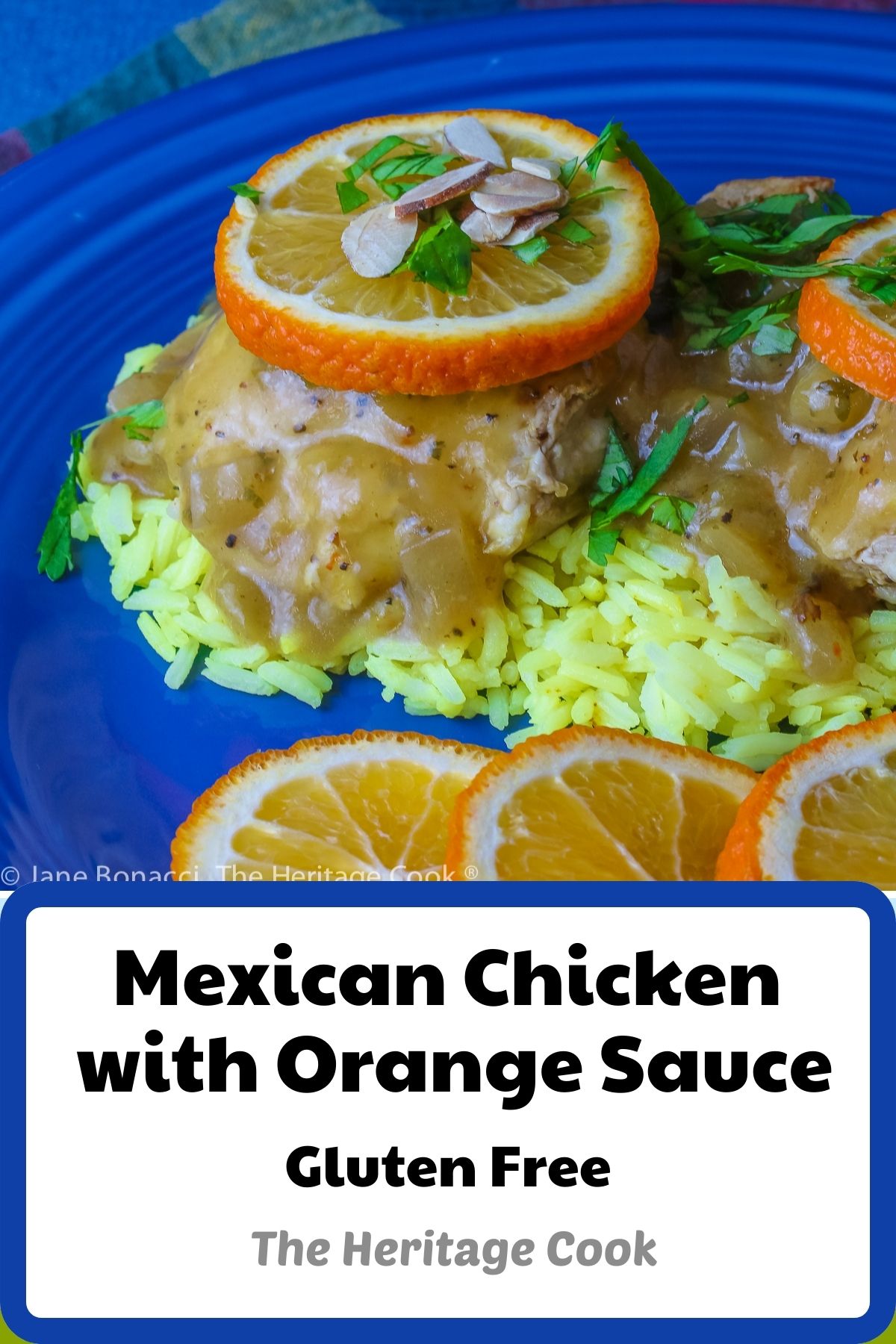 Two cooked chicken thighs resting on a pile of yellow rice on a blue plate, topped with the orange sauce, orange slices, chopped cilantro, and sliced almonds © 2023 Jane Bonacci, The Heritage Cook. 