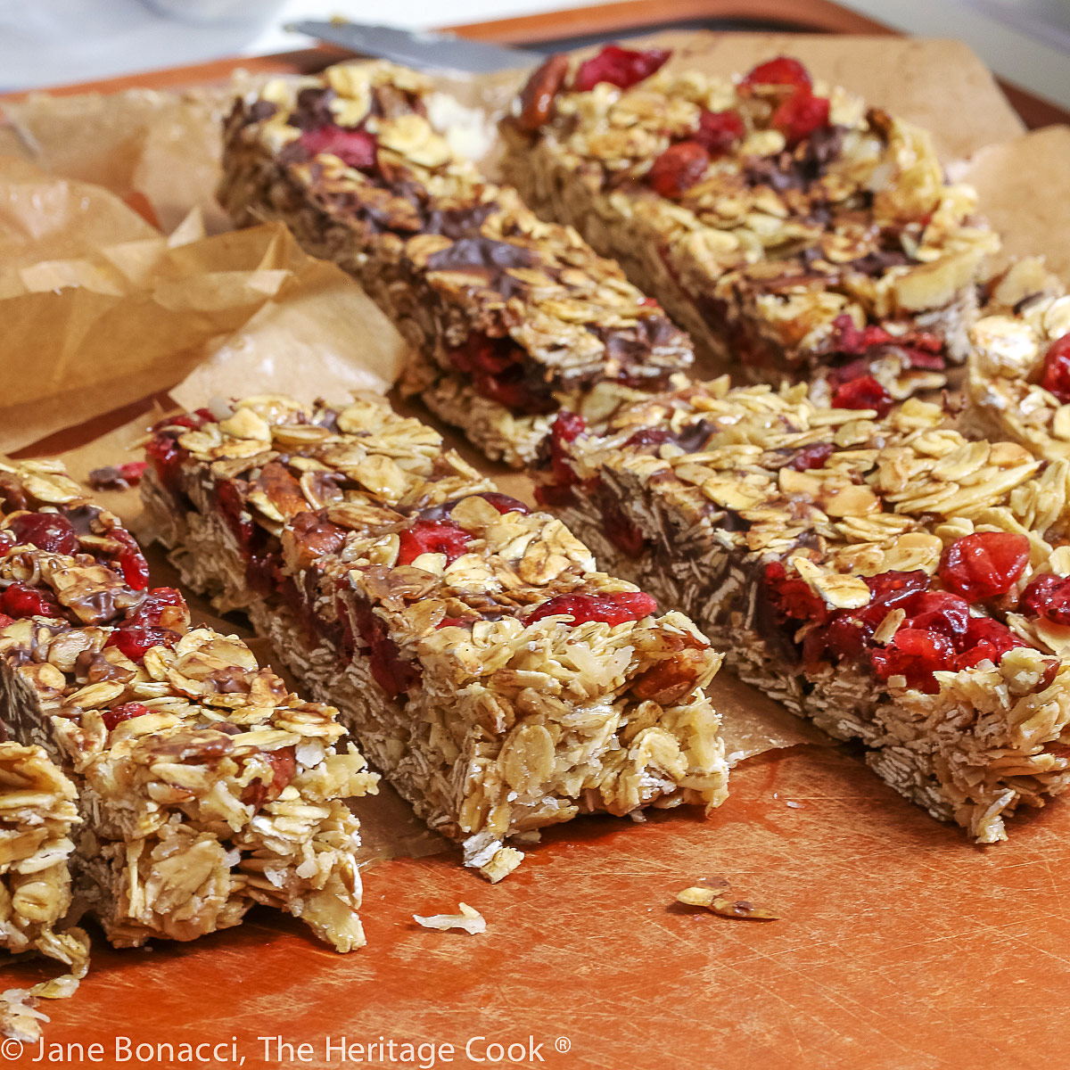 Freshly cut chewy granola bars on parchment paper and cutting board. 