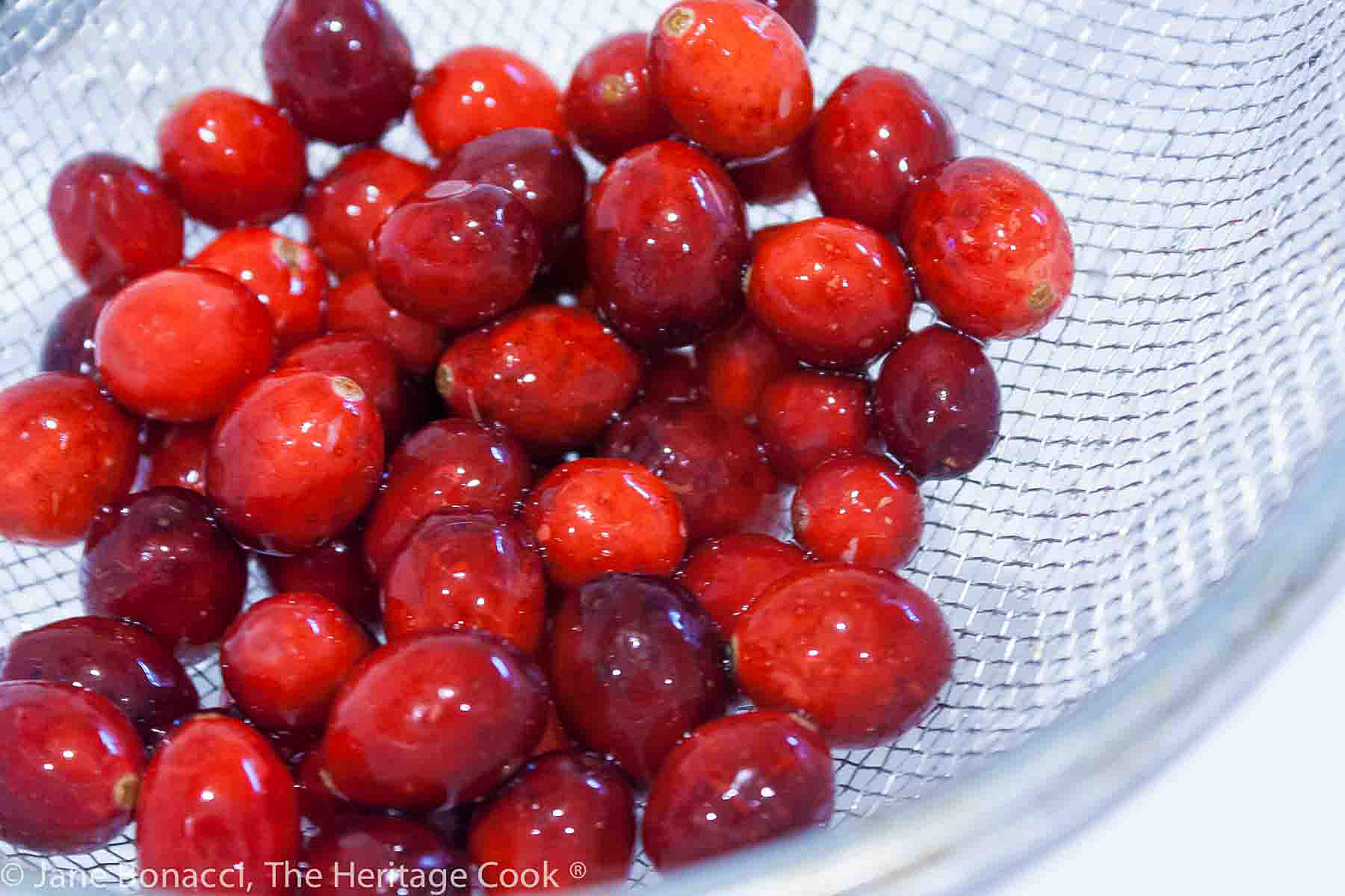 Rinsed fresh cranberries in a wire sieve. 