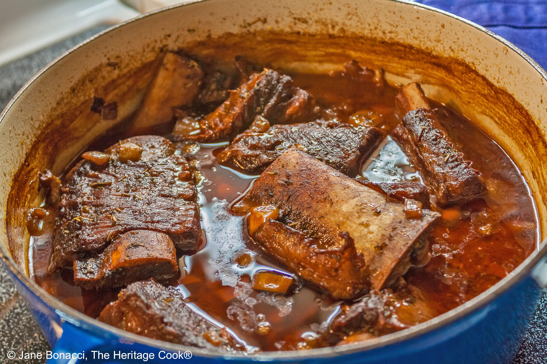 Dutch oven filled with short ribs and braising liquid ready for serving.