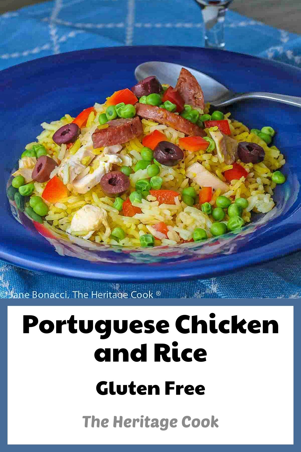 Portuguese Chicken and Rice in a dark blue bowl, with sliced chicken, sausage, and saffron rice, topped with kalamata olives, red bell pepper, and green peas © 2024 Jane Bonacci, The Heritage Cook. 