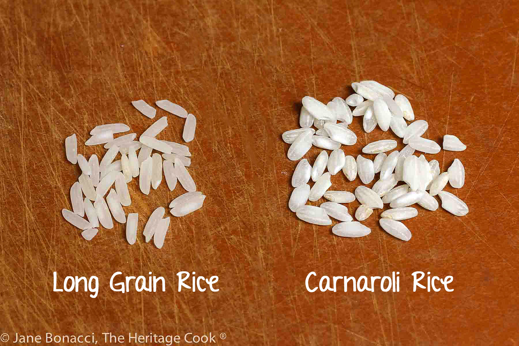Showing the difference between long grain rice and risotto rice, two piles of rice grains on a brown cutting board. 