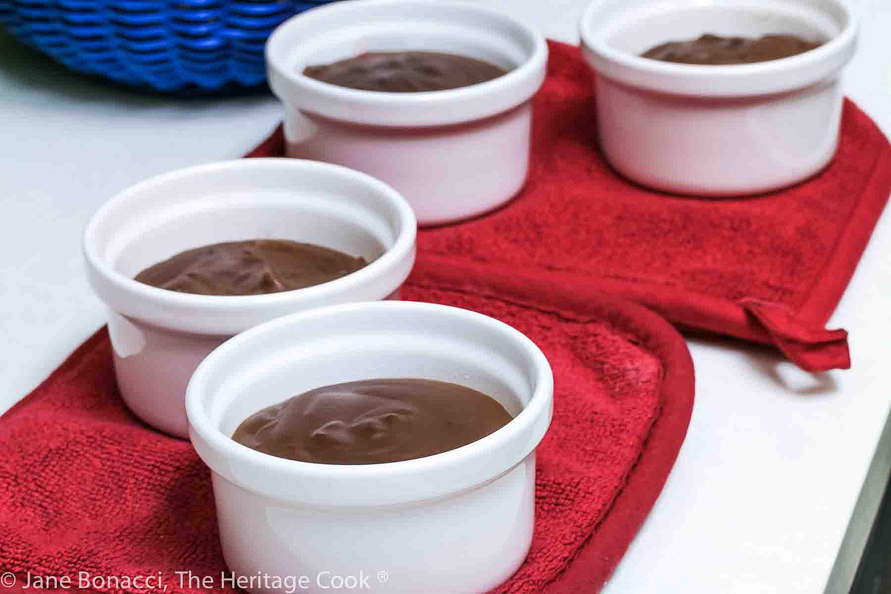 four white ramekins with hot chocolate pudding straight from the stove on red hot pads. 