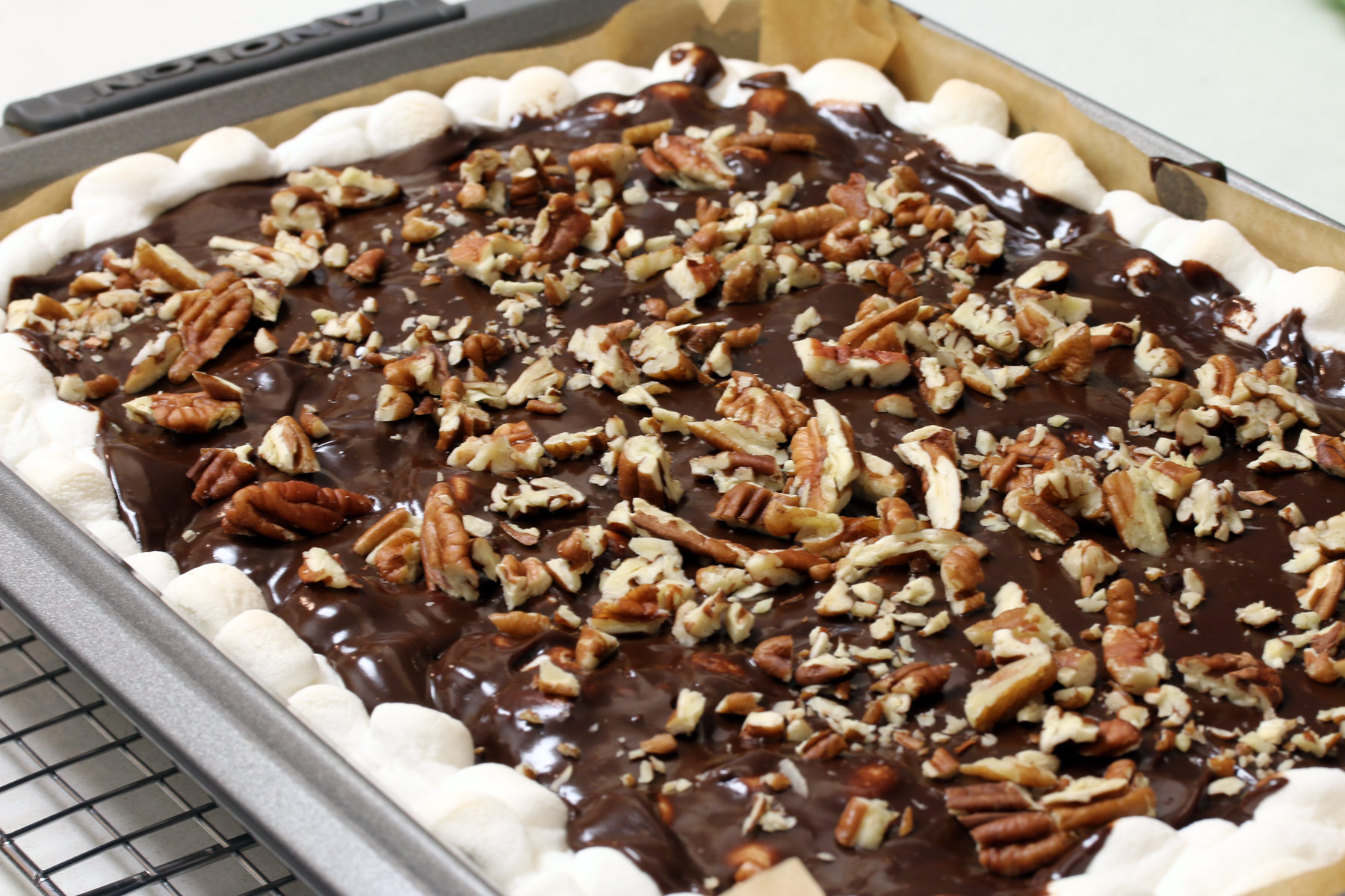Finished pan of brownies topped with marshnallows, ganache, and chopped pecans. 