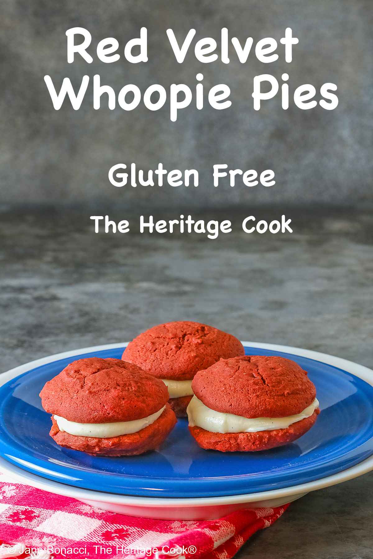 3 Mini Red Velvet Whoopie Pies clustered together in the center of a small dark blue plate on top of a larger white plate, sitting on a red and white checked cloth, perfect for the upcoming 4th of July parties © 2025 Jane Bonacci, The Heritage Cook. 