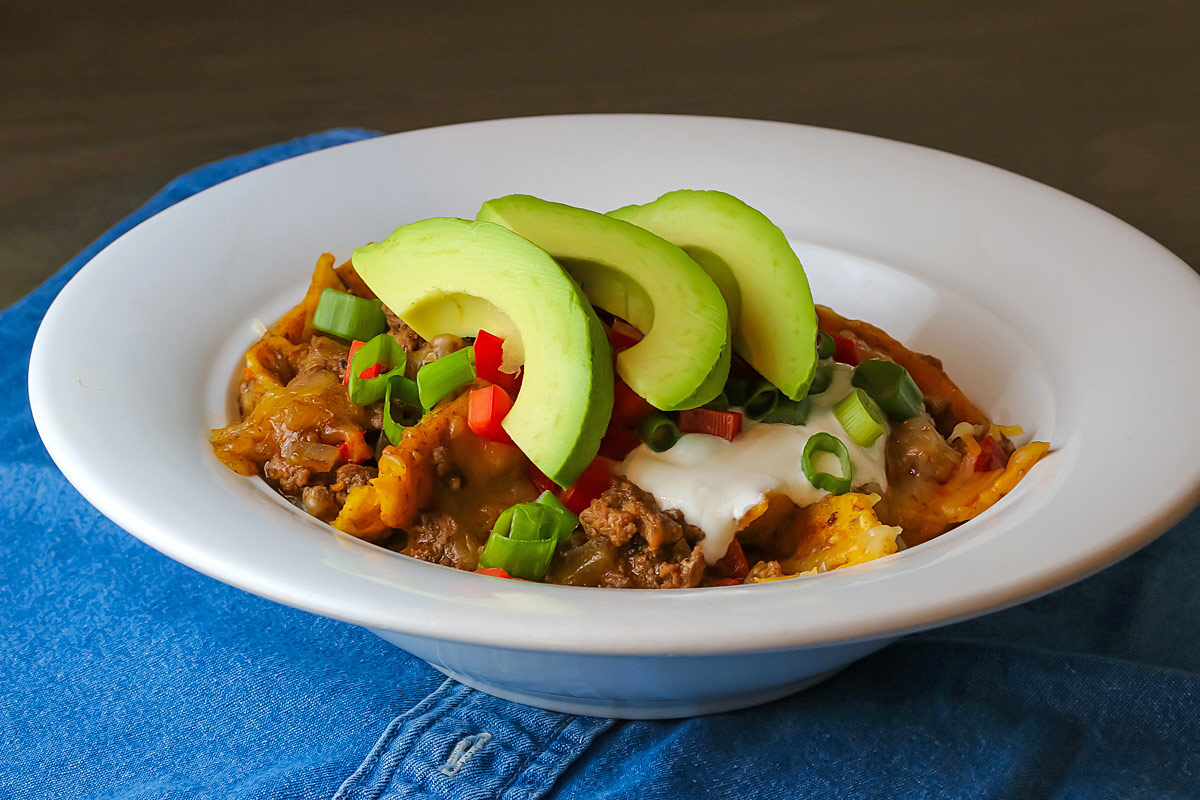White bowl filled with Beef Taco Skillet Meal topped with slices of perfect avocado. 
