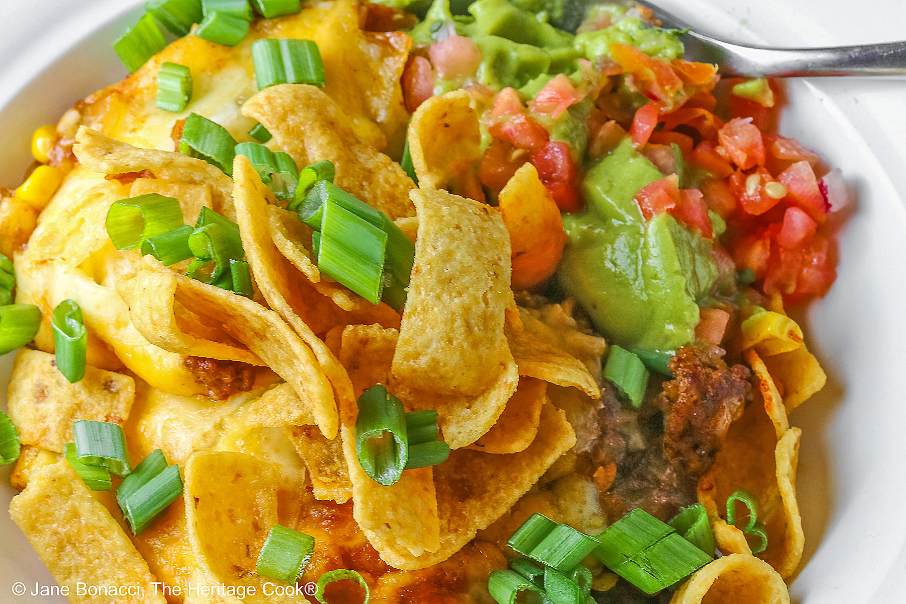 Bowl of Frito Walking Taco Casserole topped with Frito chips, guacamole, and salsa. 