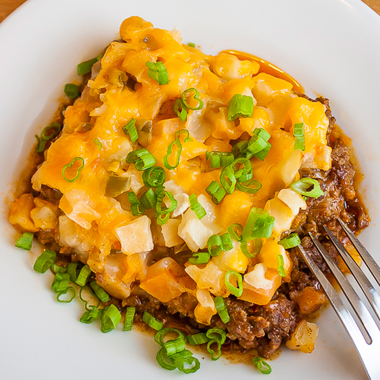 Cheesy Potato Taco Casserole in a white bowl with a fork on the edge. 