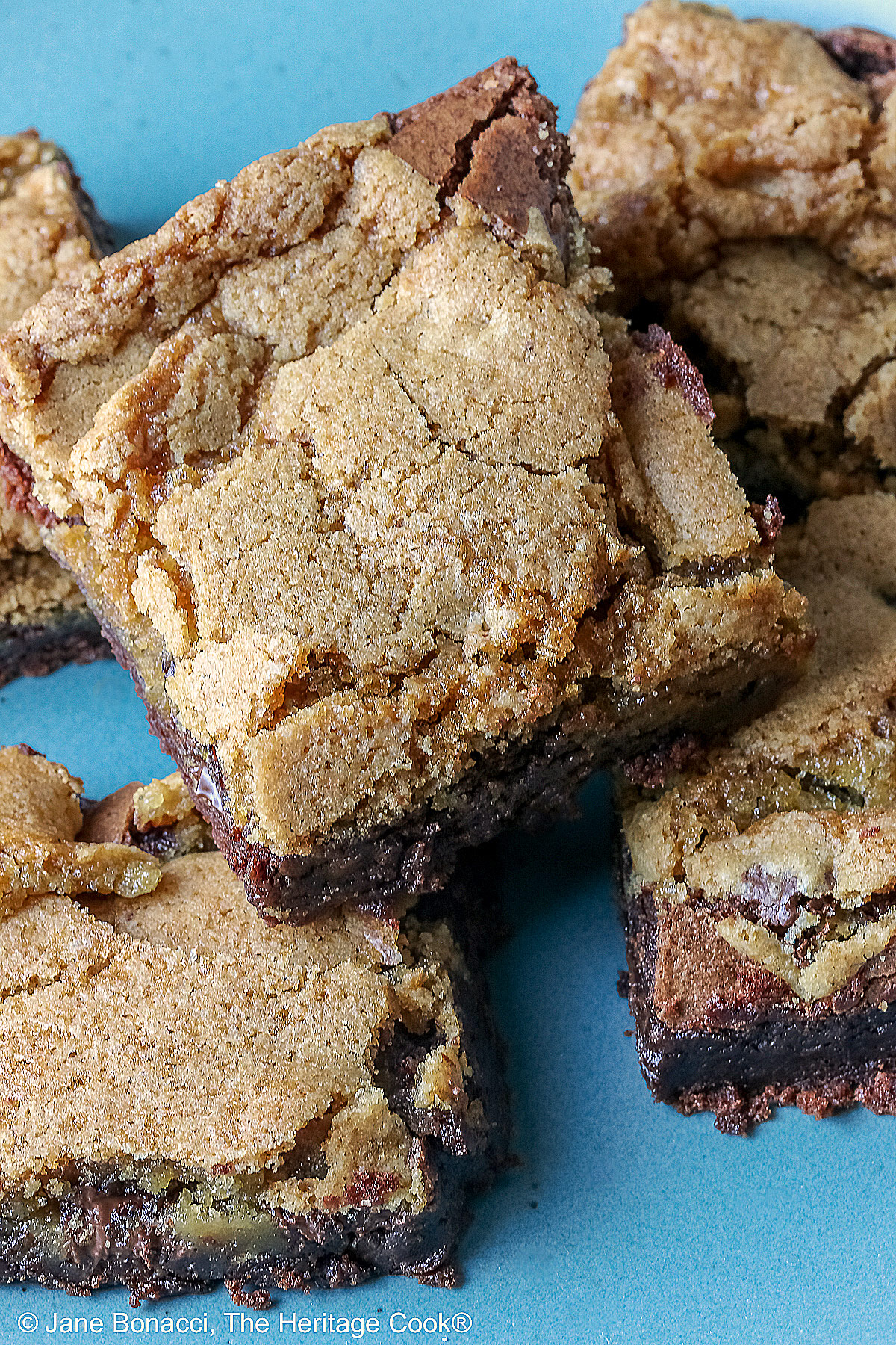 5 stacked Double Chocolate Brookies sitting on a turquoise colored plate with a medium blue cloth behind, on a mottled gray background © 2025 Jane Bonacci, The Heritage Cook.