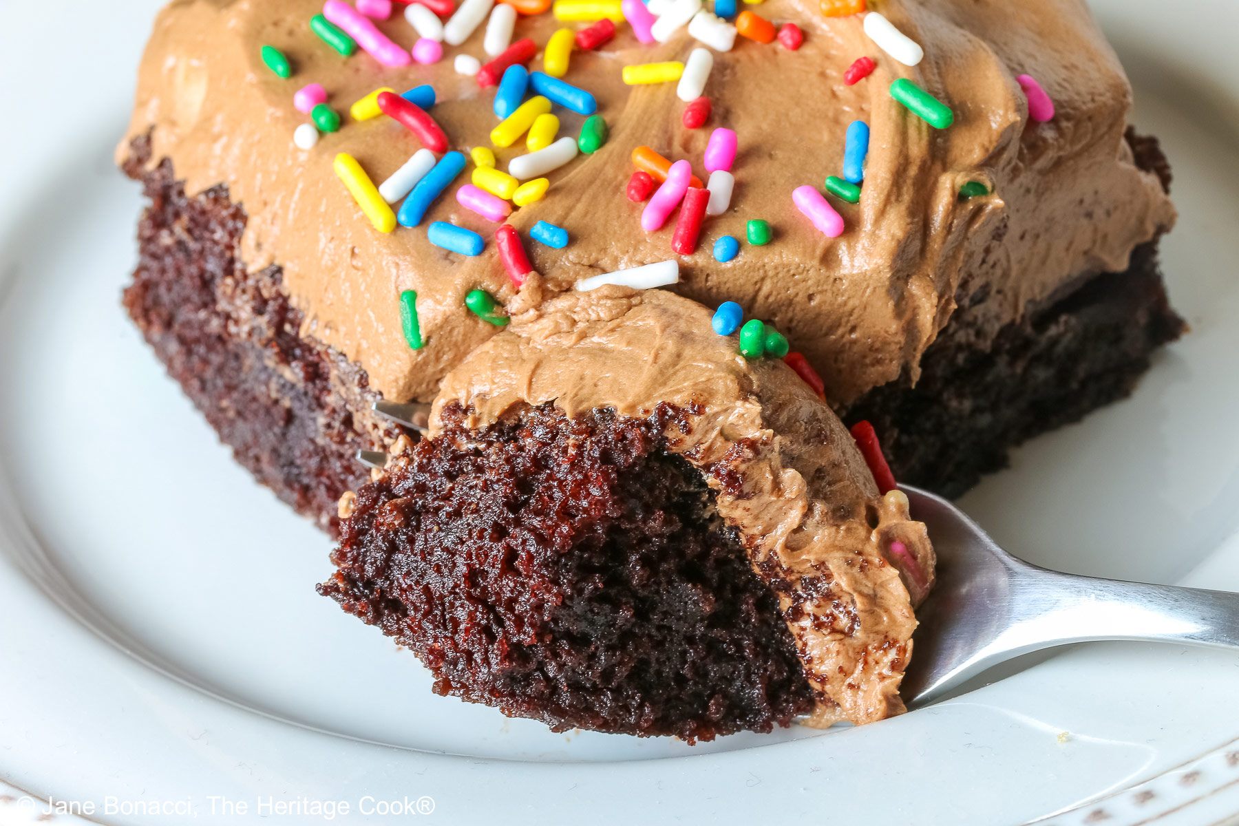Bite of cake on a fork in front of a slice of the cake.