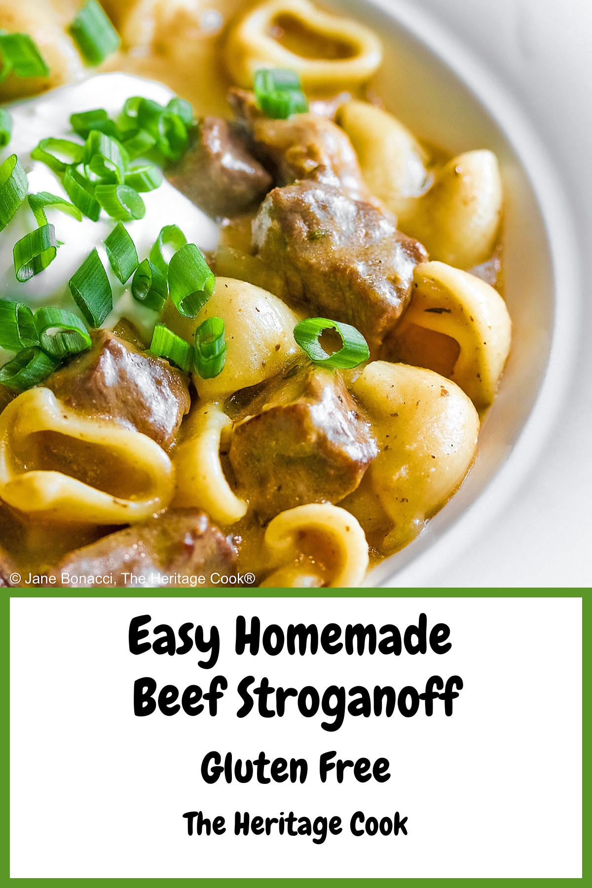 Wide rimmed white bowl filled with Easy Homemade Beef Stroganoff with pasta, beef, and sauce, topped with a dollop of sour cream and sprinkled with chopped green onions, sitting on a black background © 2025 Jane Bonacci, The Heritage Cook. 