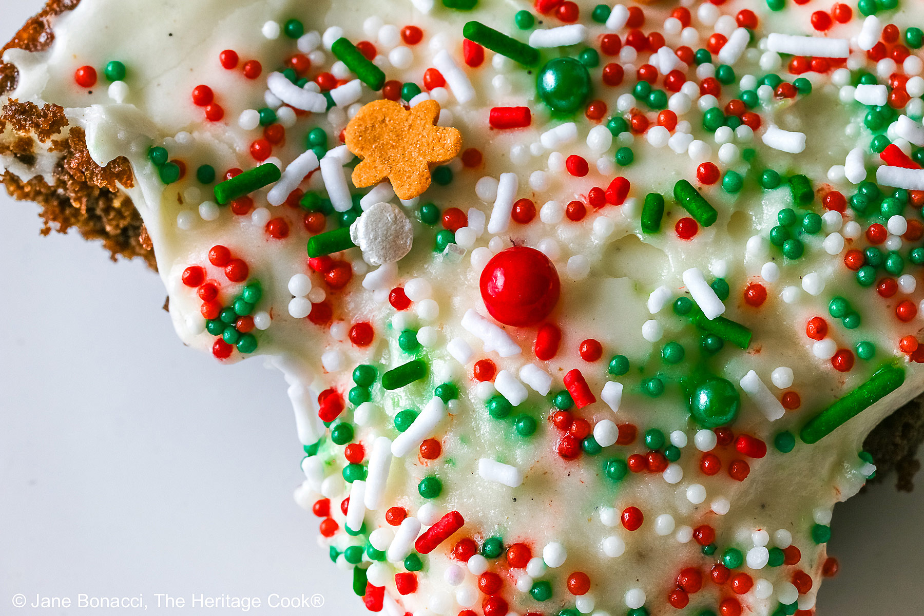 Tight close up shot of the decorations on the frosting including a gingerbread man piece.