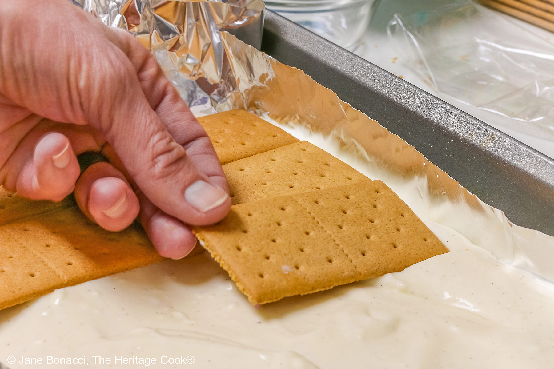 Hand laying the graham crackers on the pudding filling. 