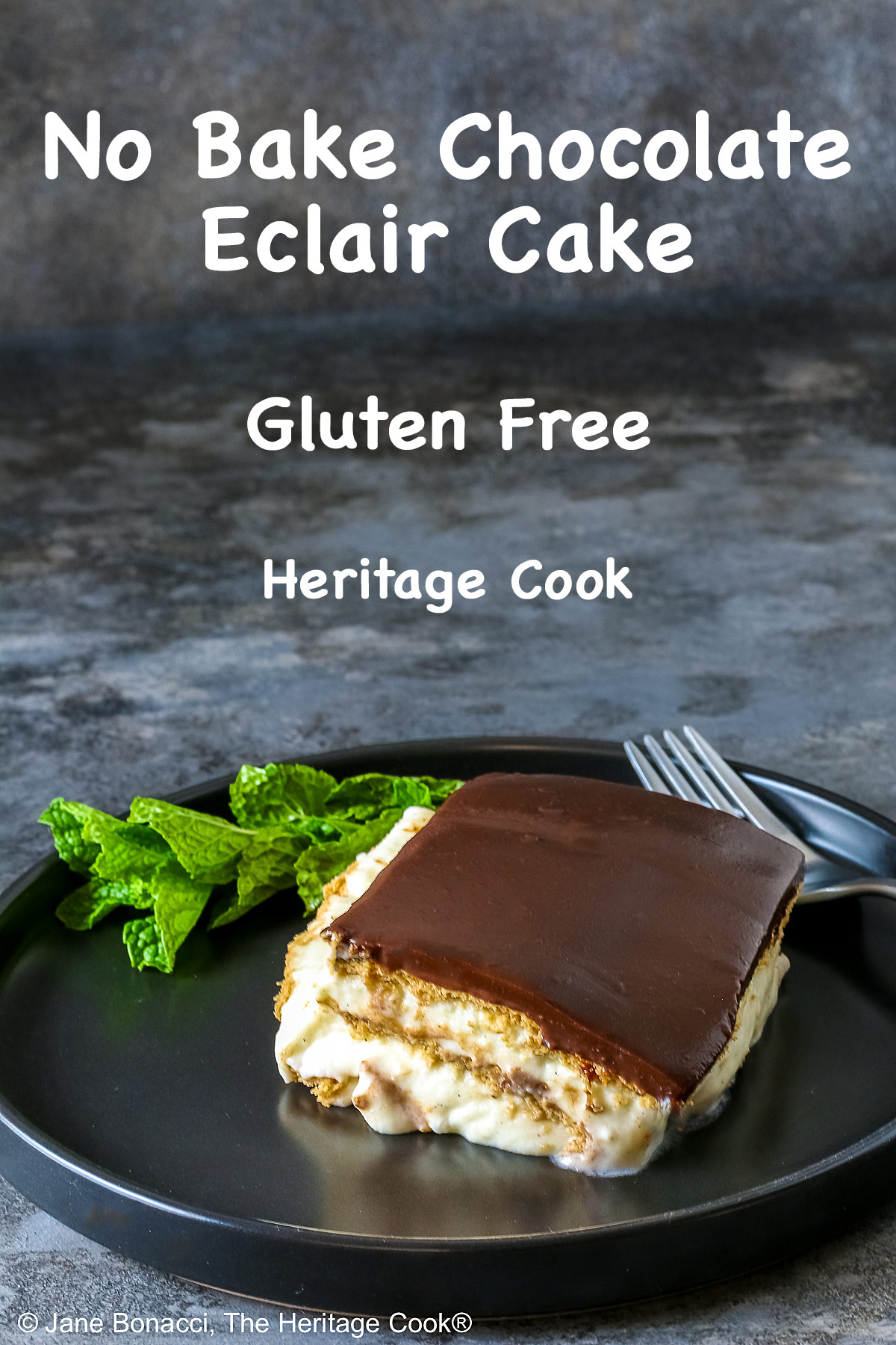 A square slice of the No Bake Chocolate Éclair Cake on a black plate with a sprig of mint and fork alongside, sitting on a muted blue and white checked cloth © 2025 Jane Bonacci, The Heritage Cook. 