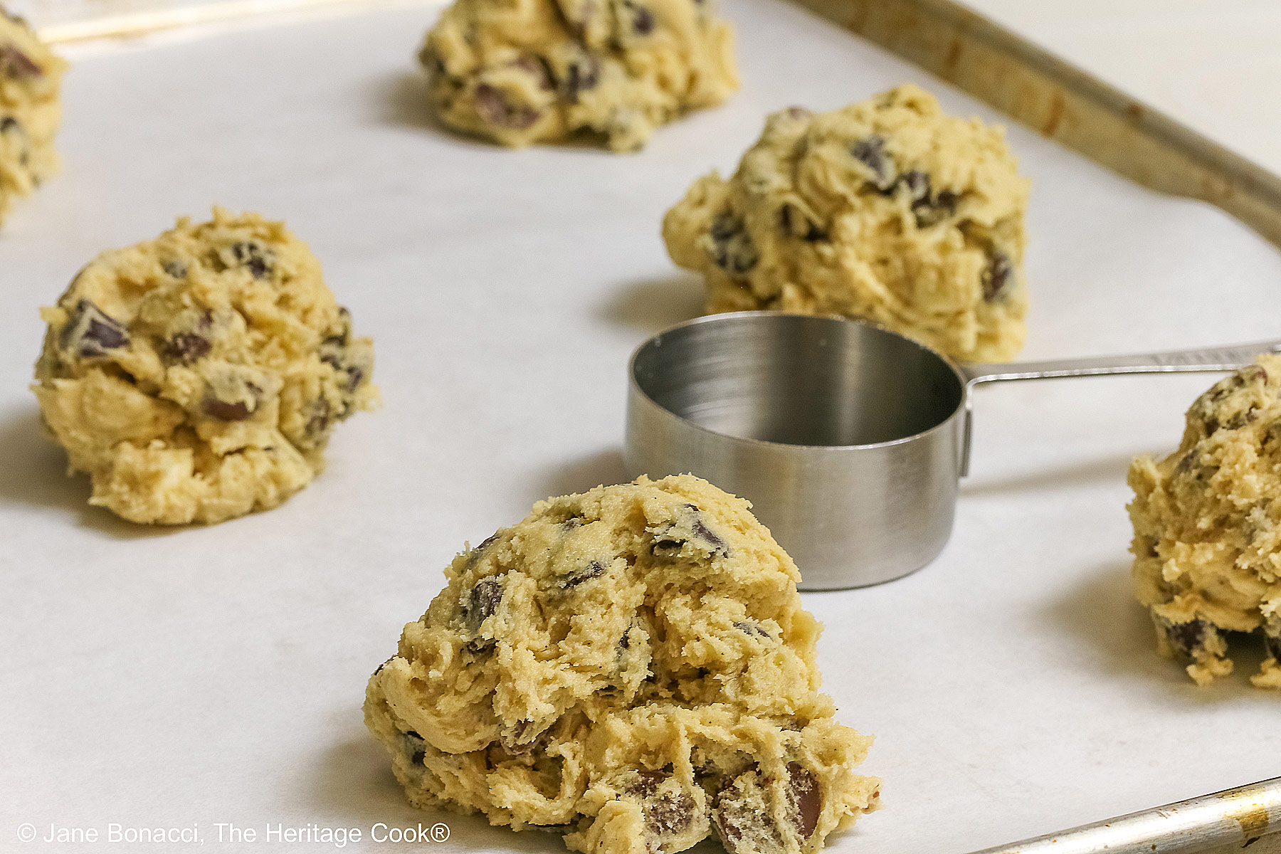 Raw dough balls with a 1/4 cup measure for size comparison - the balls are between 1/4 and 1/2 cup in size.
