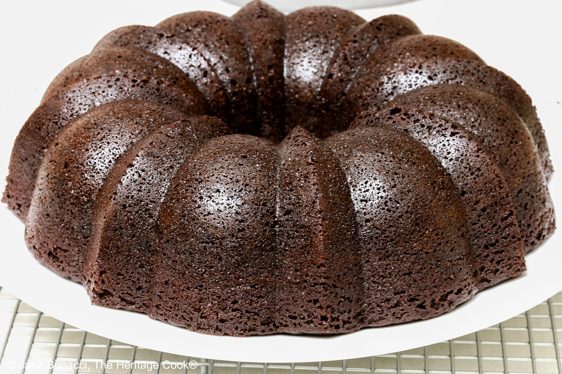 Freshly baked dark chocolate bundt cake cooling on a wire rack.