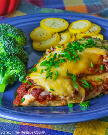 Varying angles of a salsa and melted cheese covered chicken breast with a sprinkling of chives on a blue plate surrounded by broccoli, squash coins, and lime slices, sitting on a brightly colored square cloths © 2026 Jane Bonacci, The Heritage Cook.