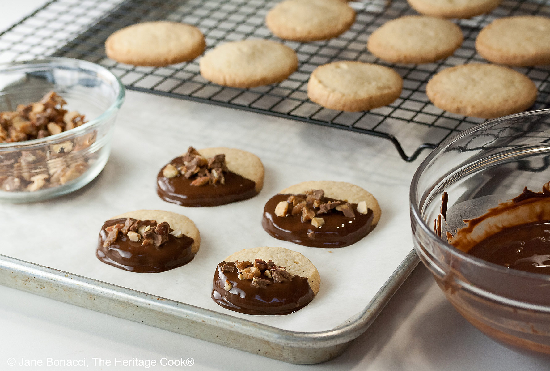 Plain cookies ready for dipping and some already dipped on parchment.