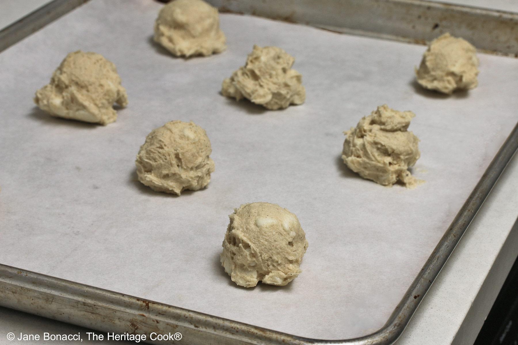 Raw portions of cookie dough on a baking sheet pan.
