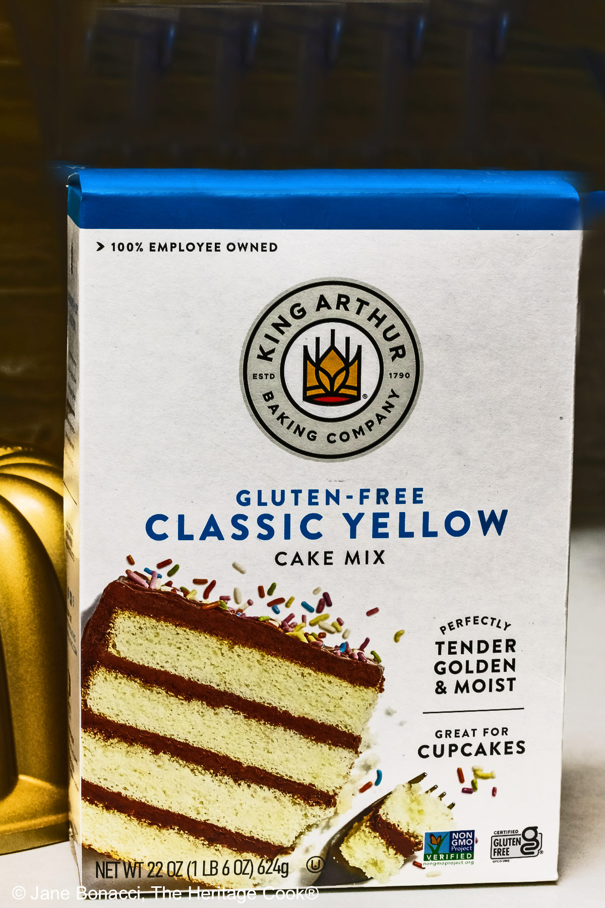 Box of King Arthur's gluten-free yellow cake mix and golden bundt pan.