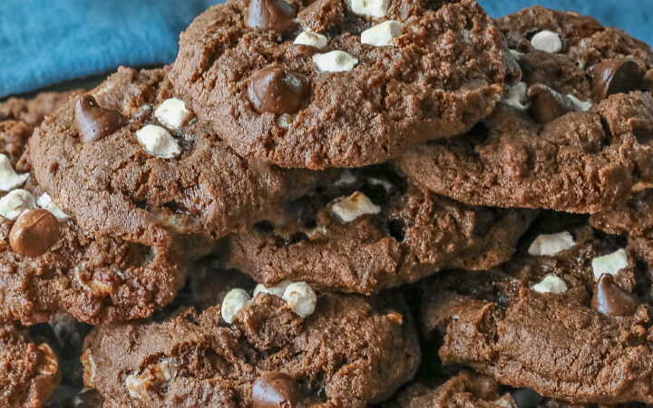Hot Cocoa Cookies stacked in a wide pyramid shape, each cookie topped with extra micro mini marshmallow bits and chocolate chips, a big pile of dark brown chocolate cookies © 2026 Jane Bonacci, The Heritage Cook.