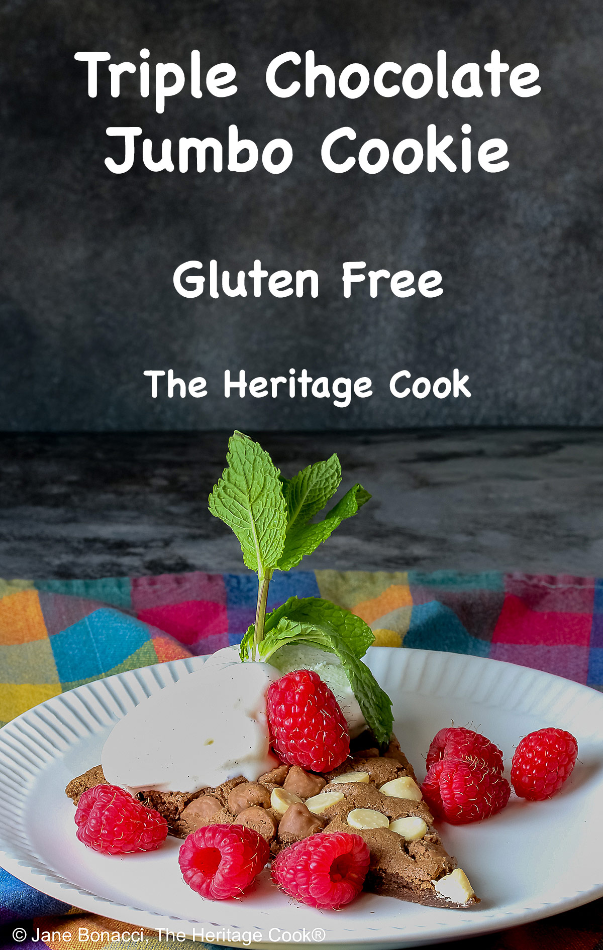 A wedge of the 10-inch (25cm) round Triple Chocolate Jumbo Cookie topped with scoops of vanilla ice cream, fresh red raspberries, and a sprig of mint © 2026 Jane Bonacci, The Heritage Cook.