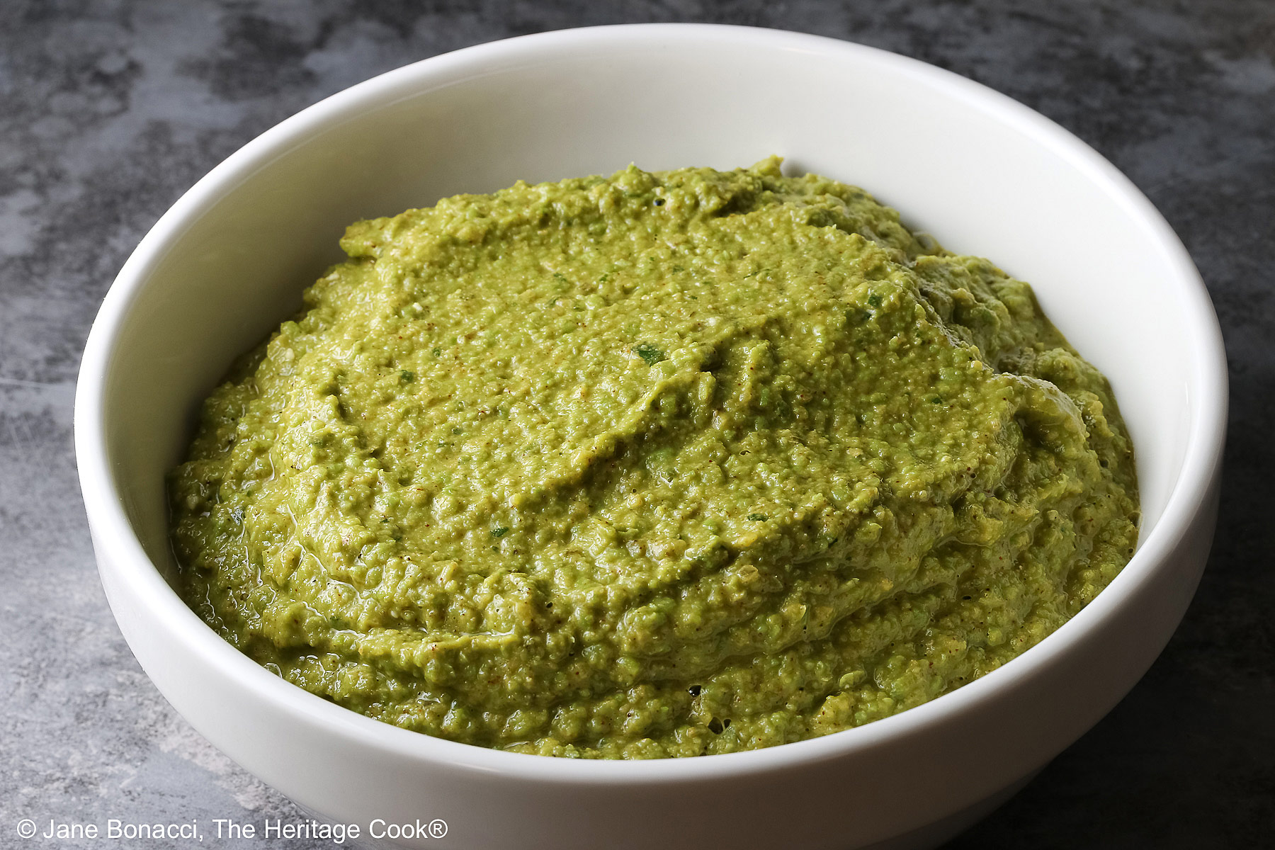 White bowl filled with the Mediterranean Pea Puree ready to spread on the crostini.