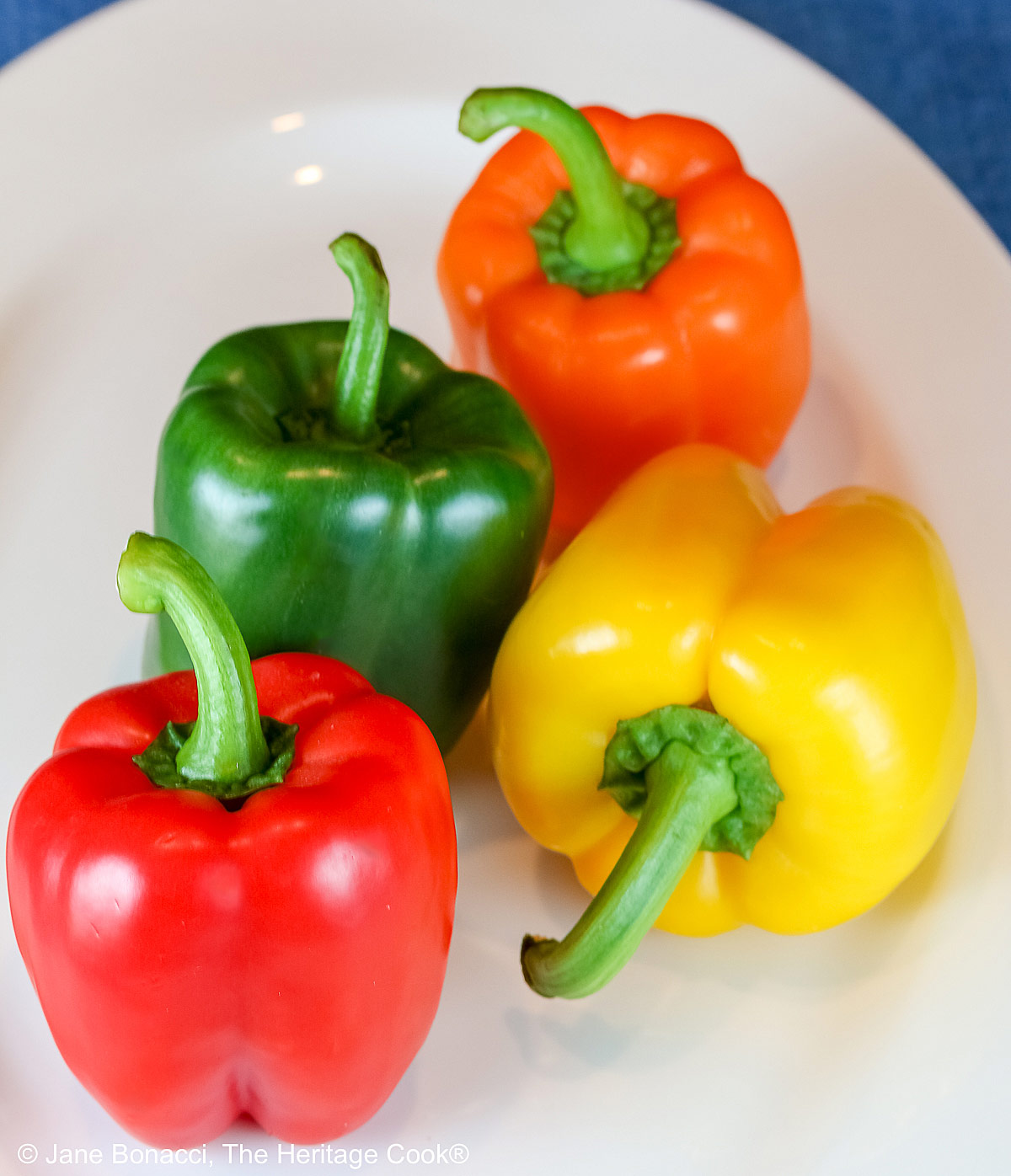 Platter of 4 bell peppers in different vivid colors.
